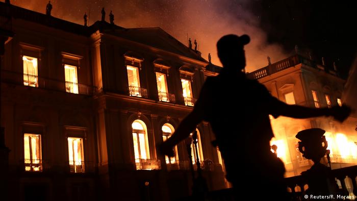 Policial evacua Ã¡rea Ã  frente do Museu Nacional durante incÃªndio da instituiÃ§Ã£o, no dia 2 de setembro de 2018. PrÃ©dio do museu aparece ao fundo, em chamas