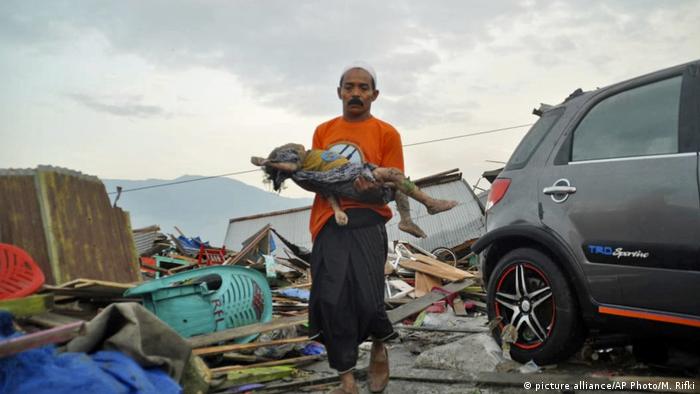 Un hombre sostiene el cadáver de un niño luego del tsunami en Palu, Indonesia.