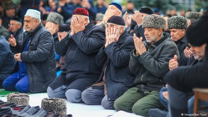 Мужчины на коленях совершают молитву во время акции протеста в столице Ингушетии Магасе