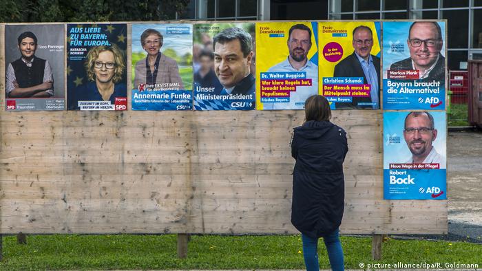A woman stands in front of a wall of campaign posters for the state election in Bavaria (picture-alliance/dpa/R. Goldmann)