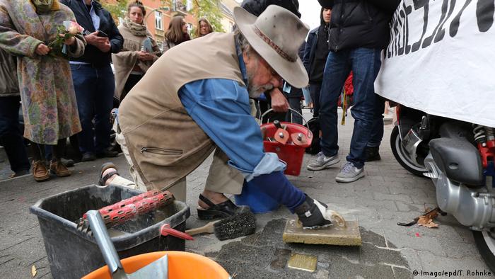 Gunter Demnig installing a stone in the ground