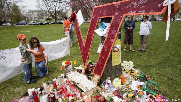  young boy points to flowers at a memorial to Virginia Tech University