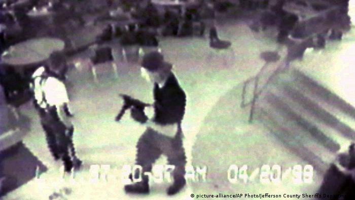 Eric Harris, left, and Dylan Klebold, carrying a TEC-9 semi-automatic pistol, are pictured in the cafeteria at Columbine High School
