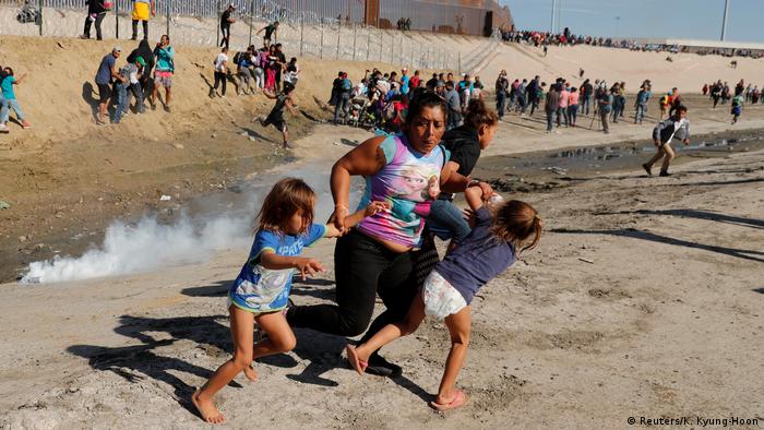 A migrant family, part of a caravan of thousands traveling from Central America en route to the United States, run away from tear gas 