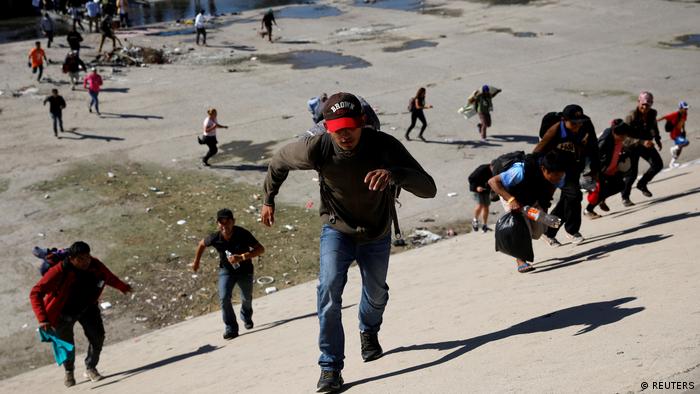 Migrants, part of a caravan of thousands traveling from Central America en route to the United States, run across the Tijuana river 