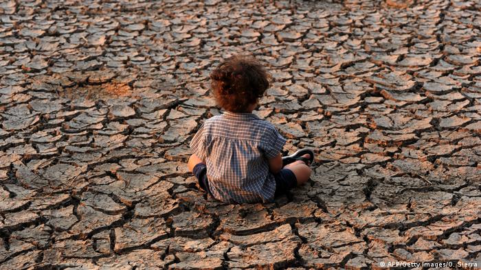 Ребенок на потрескавшейся от засухи земле