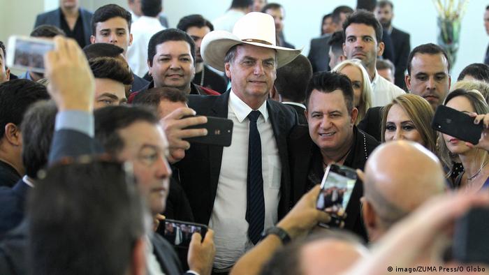 Bolsonaro, de terno, gravata e chapéu de vaqueiro, em meio a apoiadores