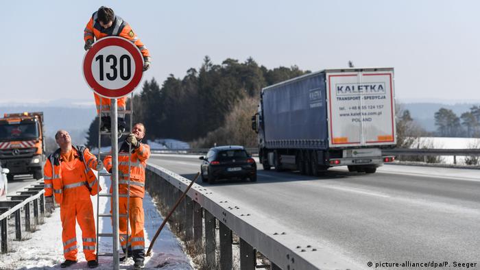 Рабочие монтируют знак ограничения скорости на автобане A81