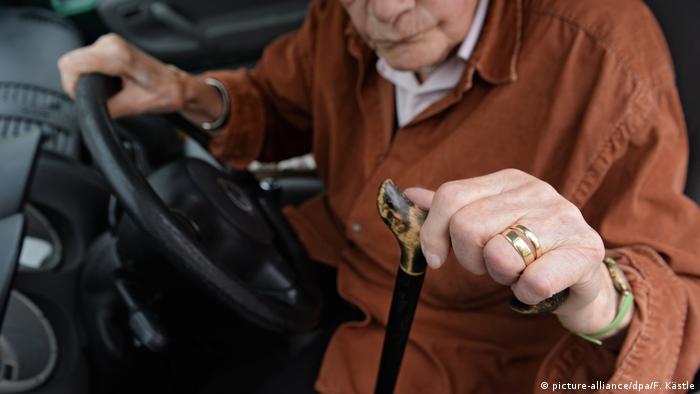 Пожилой человек с палочкой садится в автомобиль