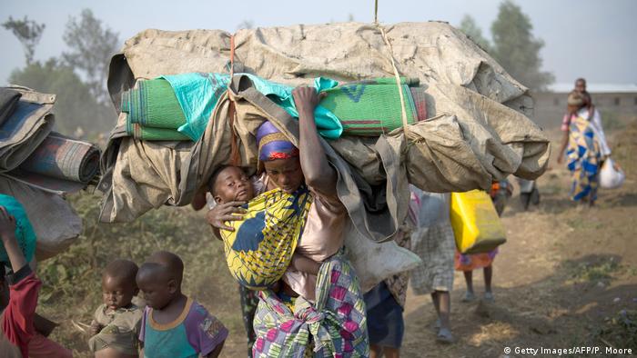 A woman carrying a child and her belongings on the move in DRC (Getty Images/AFP/P. Moore)