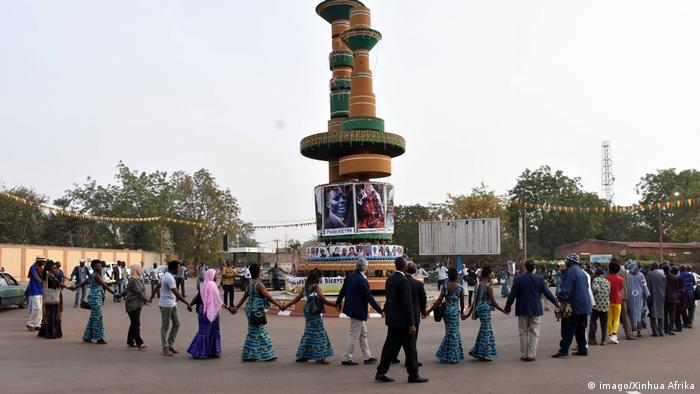 People dancing aroud a statue of two monumental film reels (imago/Xinhua Afrika)