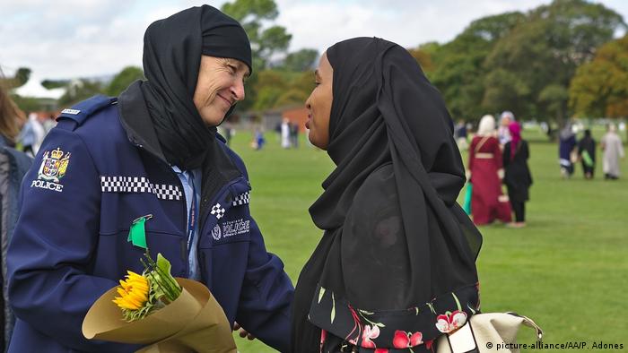 A police woman in a headscarf greets another woman in a headscarf