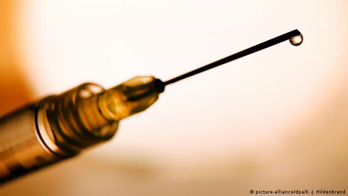 Closeup of a needle with a drop of vaccine at the end