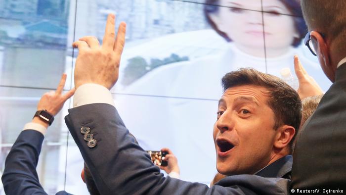 Владимир Зеленский поднимает левую руку, радуясь результатам президентских выборов