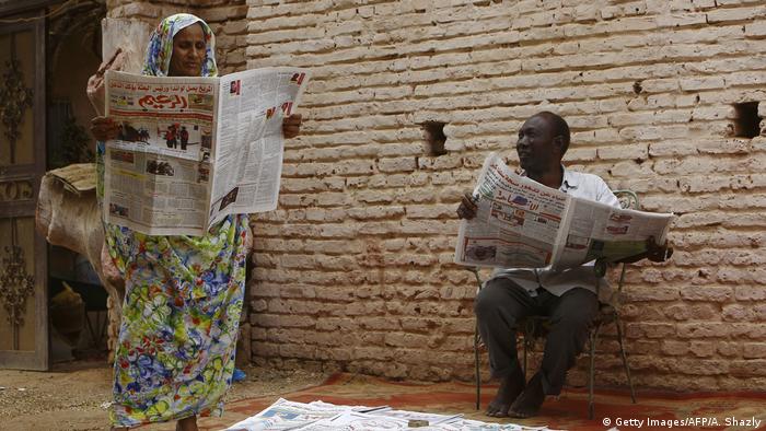 A man and a woman in Sudan read local newspapers on the street (photo: ASHRAF SHAZLY/AFP/Getty Images)