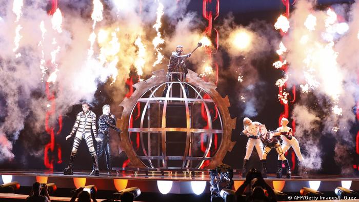 Singers and dancers in bizarre costumes on a smokey, stage with an iron cage in the middle (AFP/Getty Images/J. Guez)