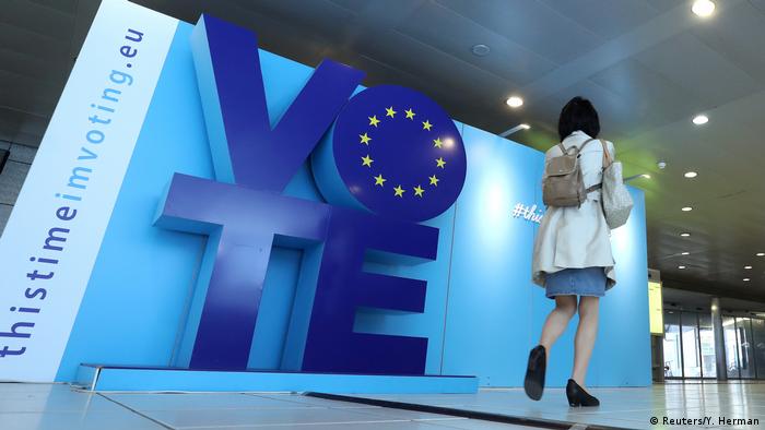 A woman walks past an advertising board for the EU elections near the European Parliament in Brussels