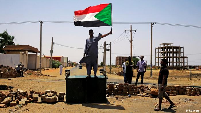 A protester stands on a block holding up the national flag (Reuters)