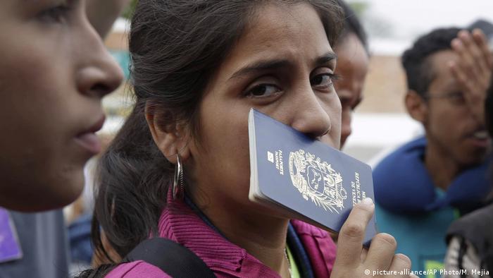 Venezuelana segura passaporte contra o rosto