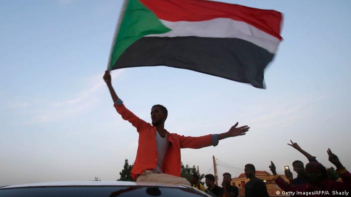 A man waves the Sudanese flag from atop a car (Getty Images/AFP/A. Shazly)