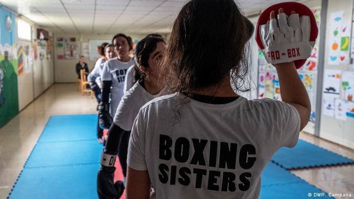 Yazidi women stand in line as they take turns hitting the upheld boxing gloves of Husna Said Yusef