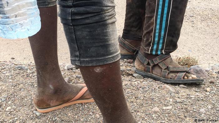 Focis on the legs and sandals of African migrants (DW/F. Facsar)