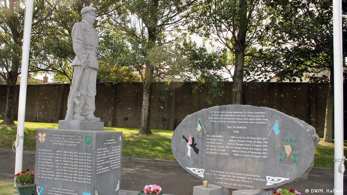 Londonderry - Derry, 02.08.2019+++A memorial at Creggan Parish Church graveyard to members of the Irish Republican Socialist Party and the Irish National Liberation army killed during fighting. A statue of a man in a balaclava, with a rifle at his side, stands below the flag of the Republic of Ireland. (DW/M. Hallam )