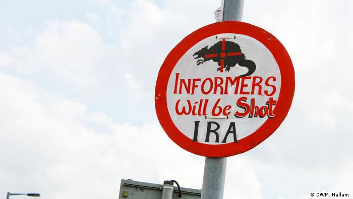 Derry, Londonderry: 02.08.2019+++An imitation road sign, erected near the site of investigative journalist Lyra McKee's murder on Creggan Estate in Derry, Londonderry. It reads: Informers will be shot, IRA. Above the lettering is a picture of a rat with a gun's crosshairs superimposed on top. (DW/M. Hallam )