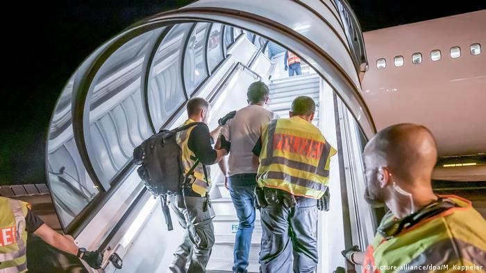 Policiais sobem escadas de avião com requerente de refúgio que teve pedido negado na Alemanha