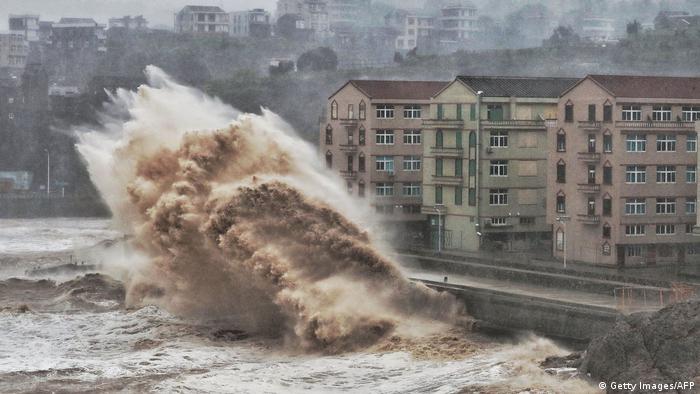 Waves hit a sea wall in front of buildings in Taizhou, China