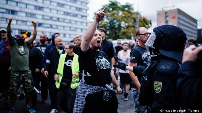 A demonstrater in Chemnitz during the 2018 far-right protests shouts at the police and raises a hand in the air (Imago Images/M. Trammer)