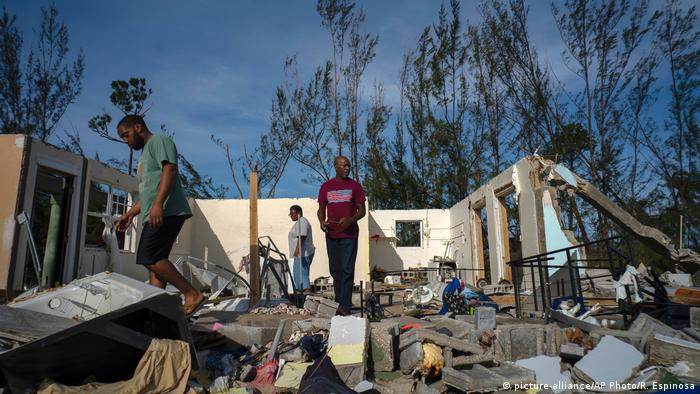 George Bolter, left, and his parents walk through the remains of his home destroyed by Hurricane Dorian in Freeport, Bahamas