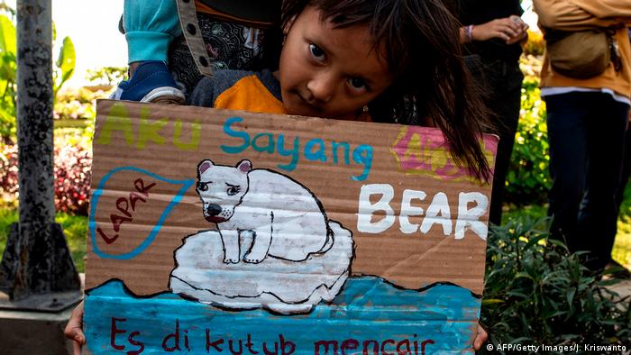 An environmental action participant from the Indonesian island of Java holds a poster in her hands