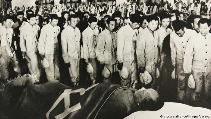 People walk past Mao Zedong at his funeral
