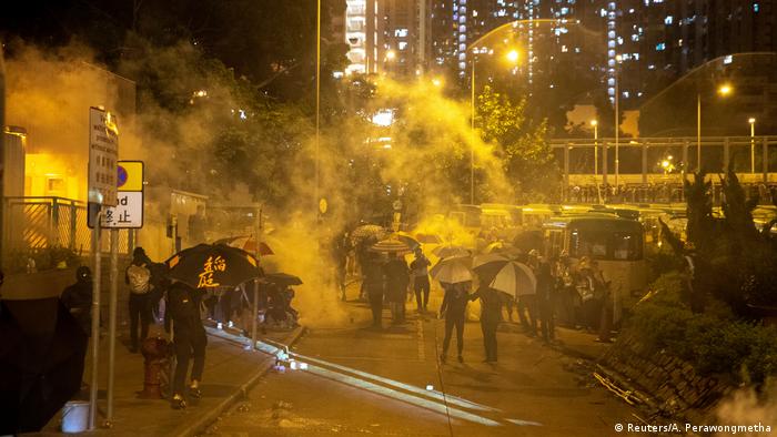 Anti-government protesters run away from a tear gas canister