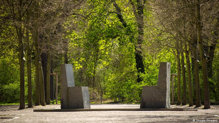 Stone slabs resembling chairs face each other in a forested setting (Imago Images)