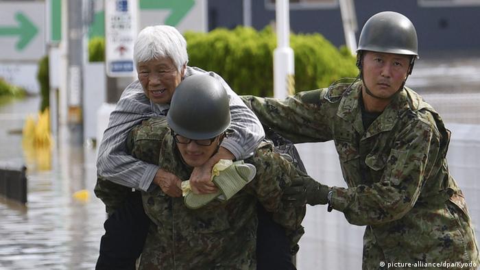 An old lady being carried on the back of a rescuer