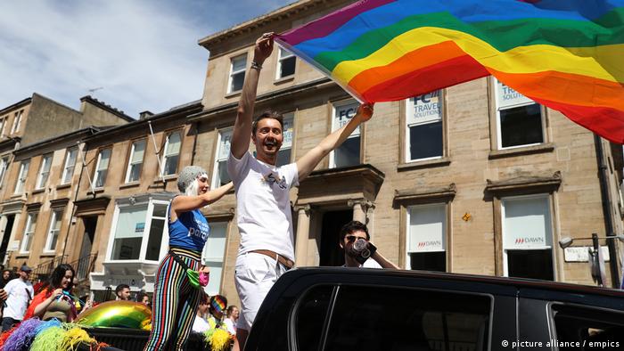 Homem com bandeira colorida na Parada Gay em Glasgow, na Escócia