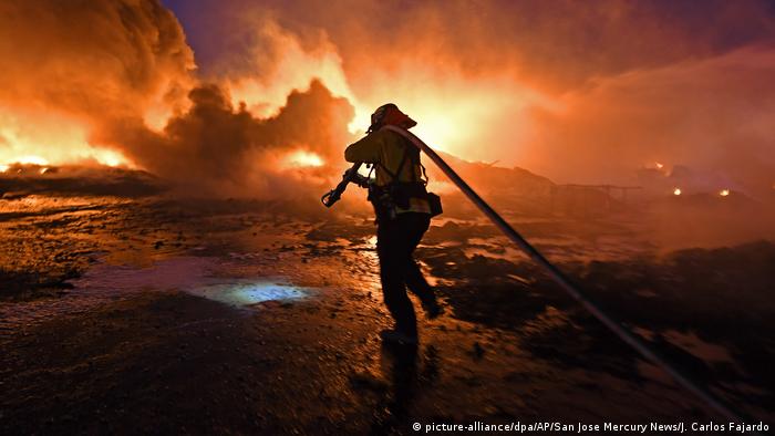 Bombeiro com uma mangueira combate incêndio florestal nos EUA