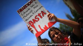 Foto de manifestante que lleva un rótulo con nombres de fallecidos en Chile
