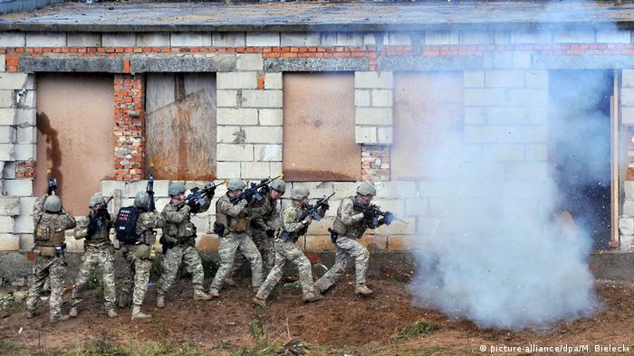 Soldiers aim weapons and prepare to storm a building on a training exercise