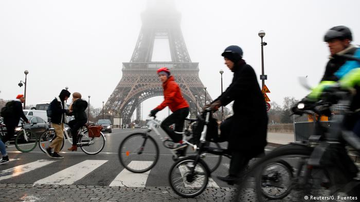 Pessoas de bicicleta diante da Torre Eiffel