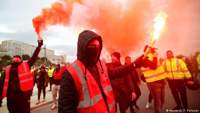 Protesters light red flares during the French general strike