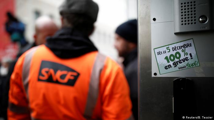 A rail worker wearing a fluorescent jacket with an SNCF train company logo on the back