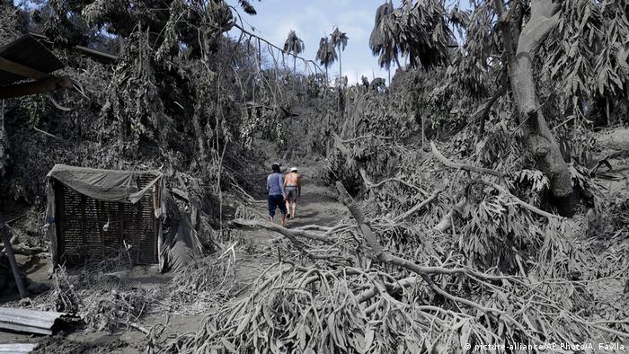 Two people walk through an ash-covered village after the Taal volcano erupted