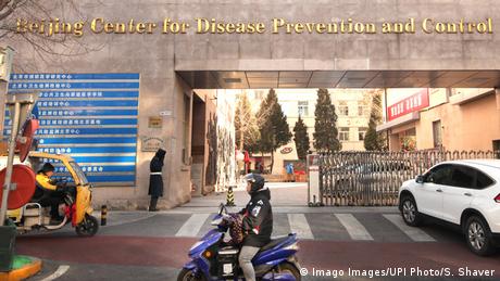 Una persona pasa con un scooter frente a un centro de salud y prevención en Beijing.