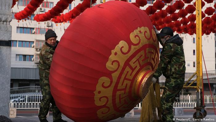 Two Chinese soliders remove a giant lantern as they unbuild decorations for the Lunar New Year celebrations canceled due to the coronavirus (Reuters/C. Garcia Rawlins)