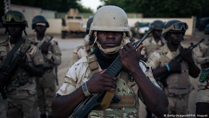 Cameroonian armed forces stand holding guns