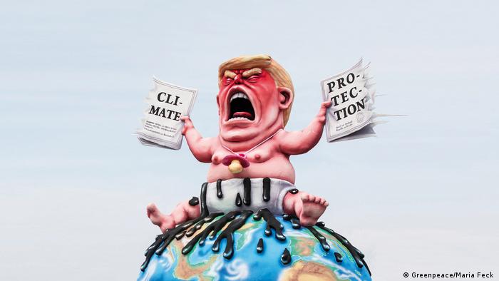 Trump figurine as a baby in diapers, seated on a globeand trearing apart a climate accord (Greenpeace/Maria Feck )
