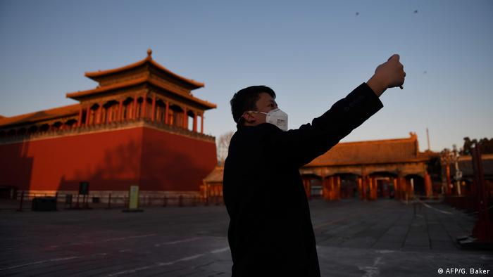 a man taking a selfie, Chinese buildings in the background (AFP/G. Baker)